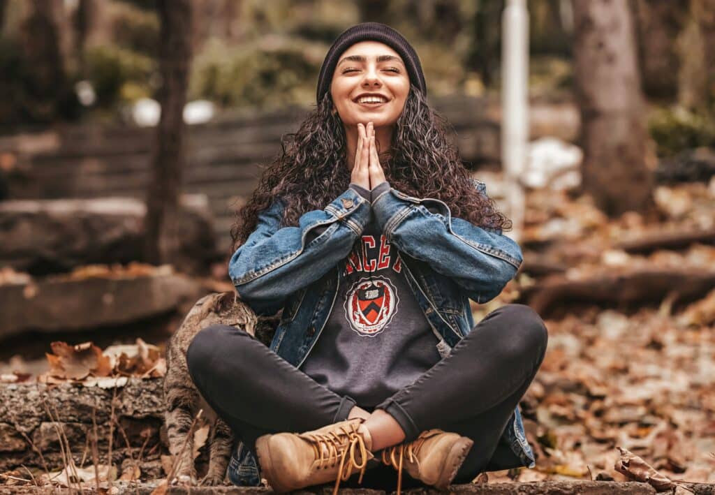 teenage girl meditating in the woods smiling